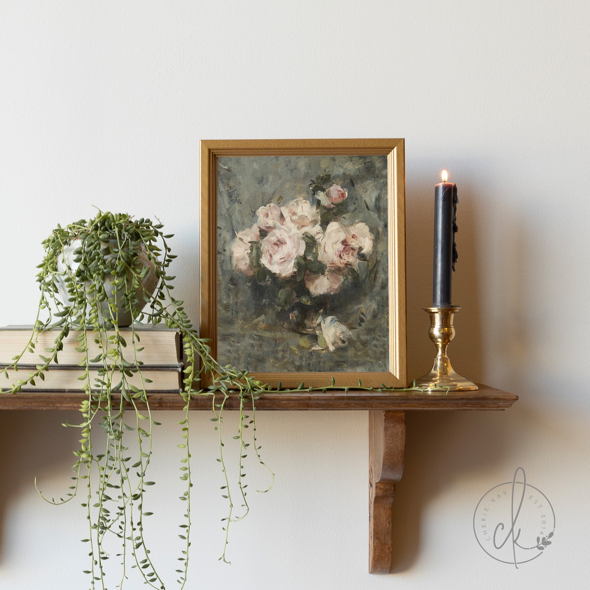 Small framed botanical painting featuring soft pink roses in an elegant gold frame, displayed on a rustic wooden shelf with a black candle and trailing succulent. Perfect for vintage-inspired or cottagecore décor and available in multiple sizes.