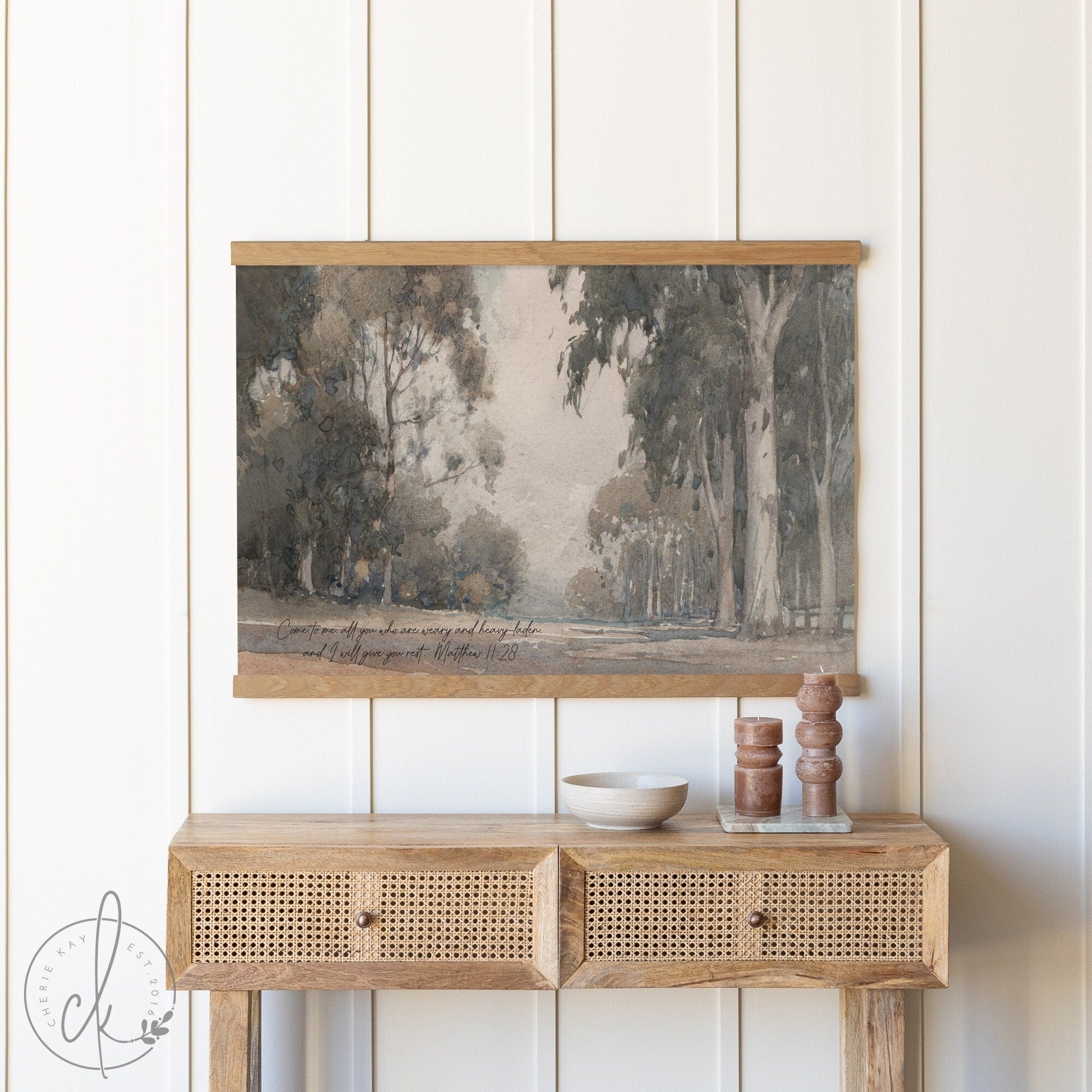 Vintage woodland art print with a forest scene and scripture quote, hanging above a rustic wooden console table.