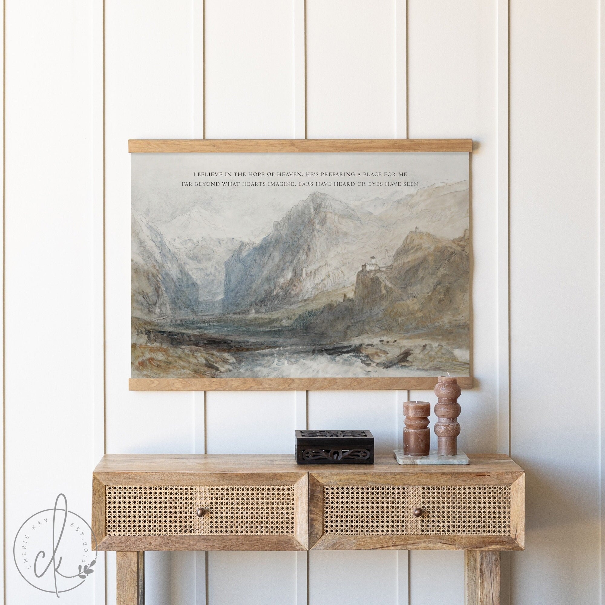 Vintage illustrated mountain landscape art tapestry hanging above a rustic wooden console table, featuring an inspirational quote. Perfect wall decor for living room, bedroom, or entryway to add a touch of nature-inspired elegance.