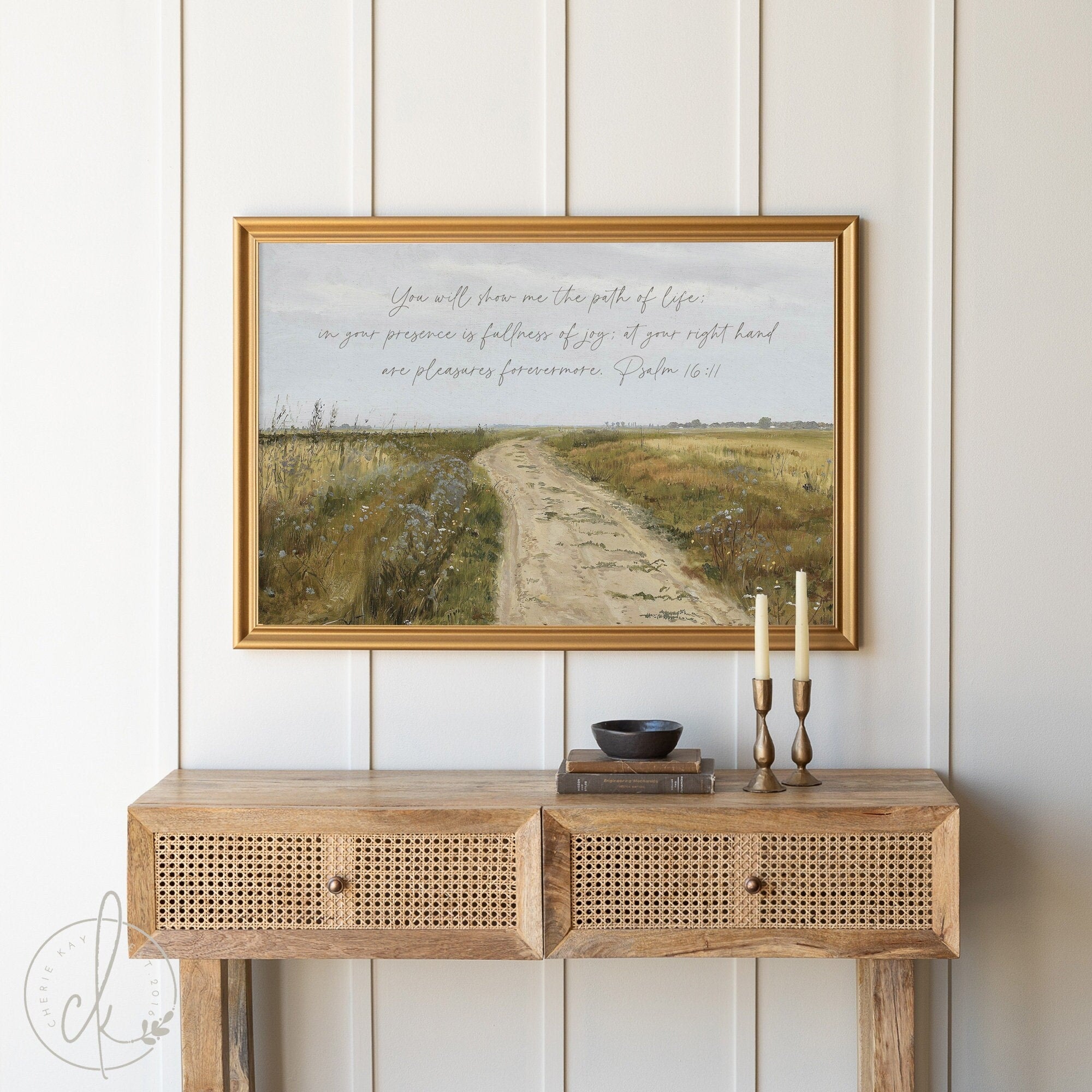 Farmhouse-style landscape painting featuring Psalm 16:11 Bible verse in elegant gold frame, displayed above a rustic wooden console table with two candles and decorative bowl