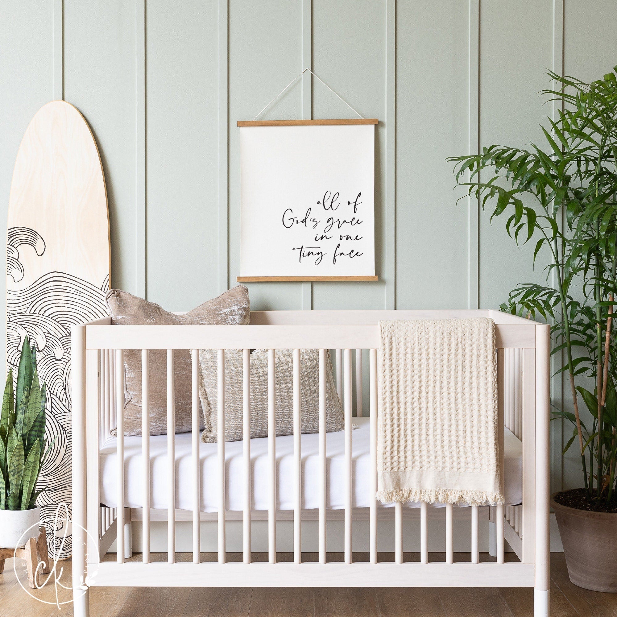 Neutral nursery with light wood crib, cozy pillows, and a canvas sign that reads All of God&#39;s grace in one tiny face, creating a serene and faith-inspired baby room decor.