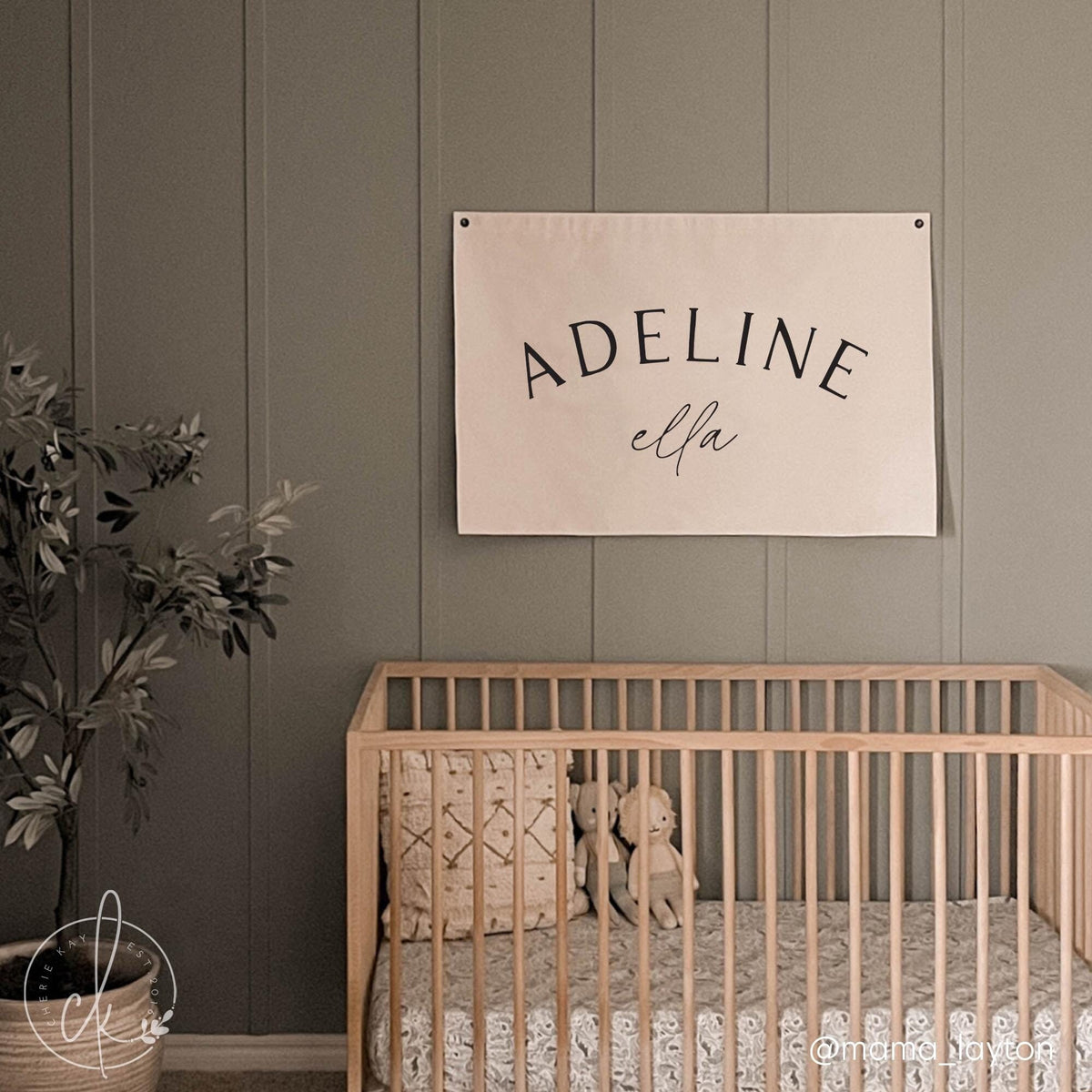 Personalized baby girl name canvas sign hanging above a wooden crib in a neutral-toned nursery, in elegant black fonts. Ideal for nursery decor, baby shower gifts, or newborn keepsakes.