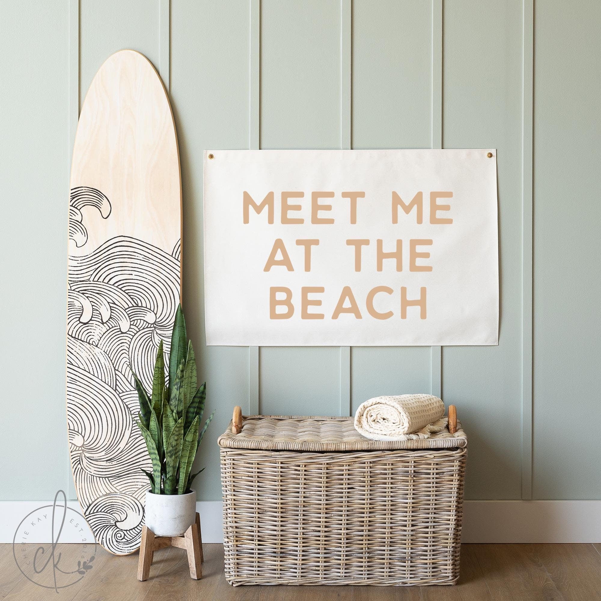 Coastal canvas sign with Meet Me at the Beach text, displayed in a beach-themed room with a surfboard and wicker basket, ideal for beach house or coastal decor.