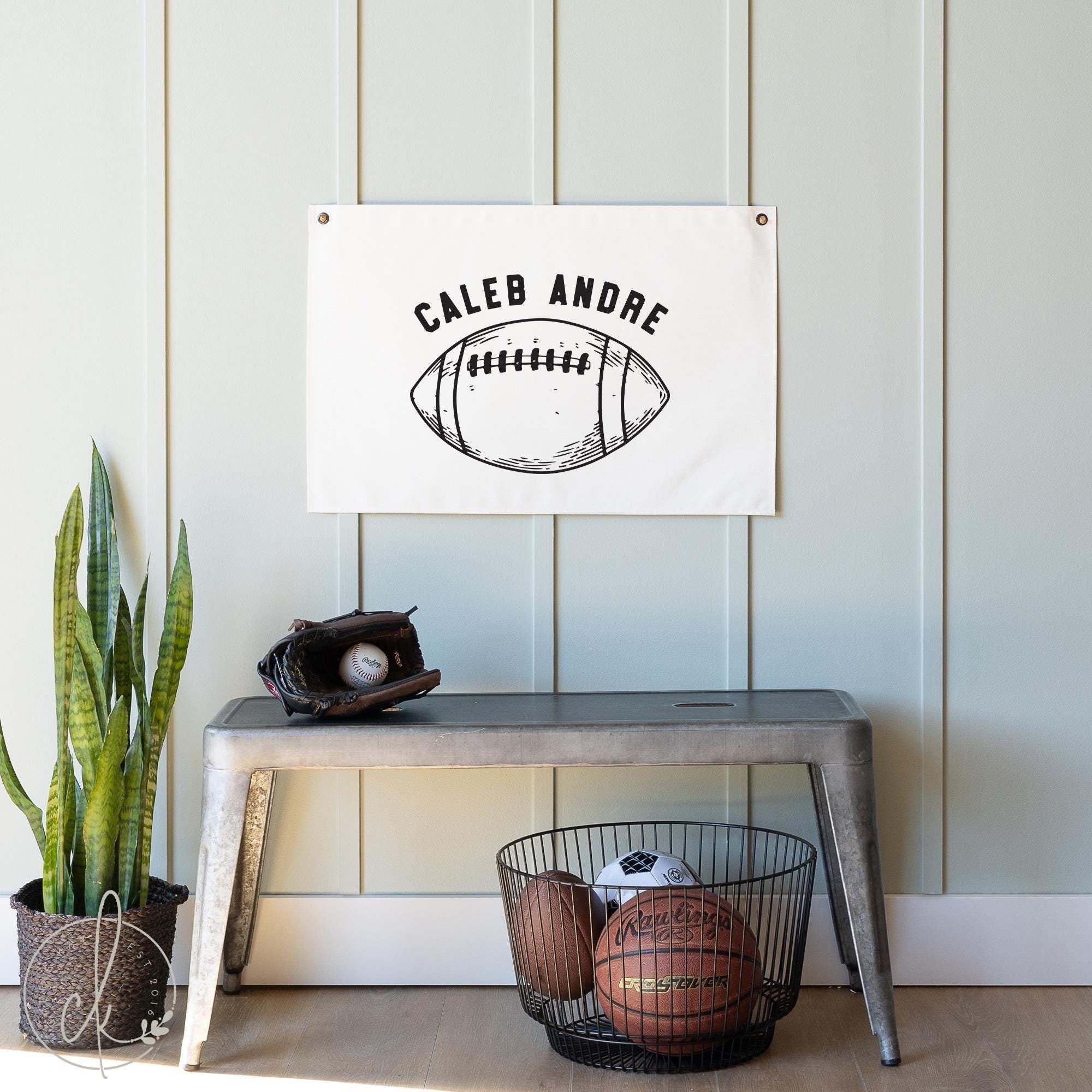 Personalized football canvas flag with a name printed above a hand-drawn sketch of a football, displayed on a wall in a boys room. Perfect for boys nursery, bedroom, playroom, or teen room.