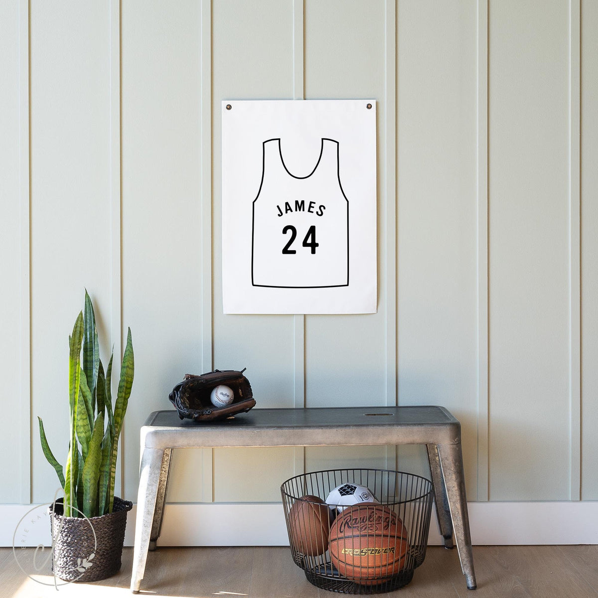 Custom basketball jersey canvas wall art with personalized name and number, displayed in a stylish boy&amp;#39;s room with sports-themed decor, featuring a basketball and baseball glove on a bench below the sign.