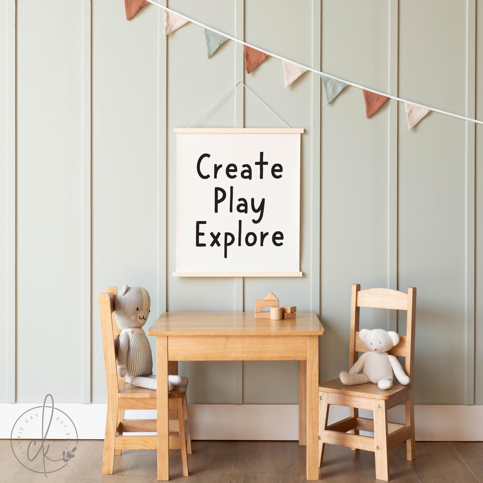 A cozy and minimalistic childrens playroom featuring a wooden table and chairs set. Two plush toys are seated on the chairs. A simple, modern wall sign displays the words - Create Play Explore - adding an inspiring and playful touch to the room.