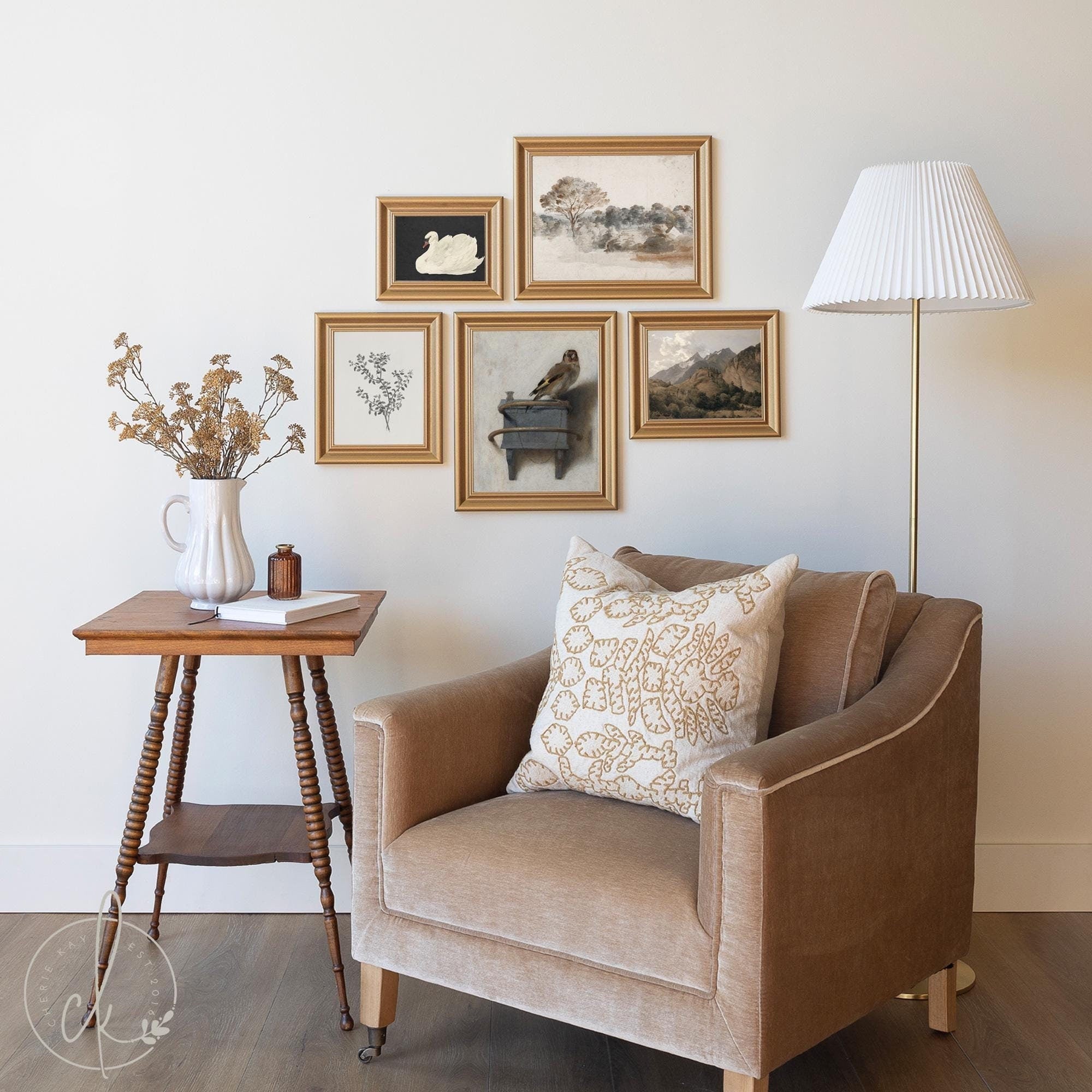 Cozy reading nook with a beige armchair, a wooden side table, and a gold-toned floor lamp. A gallery wall with five framed nature-inspired prints hangs above, complementing the neutral, earthy tones of the decor.