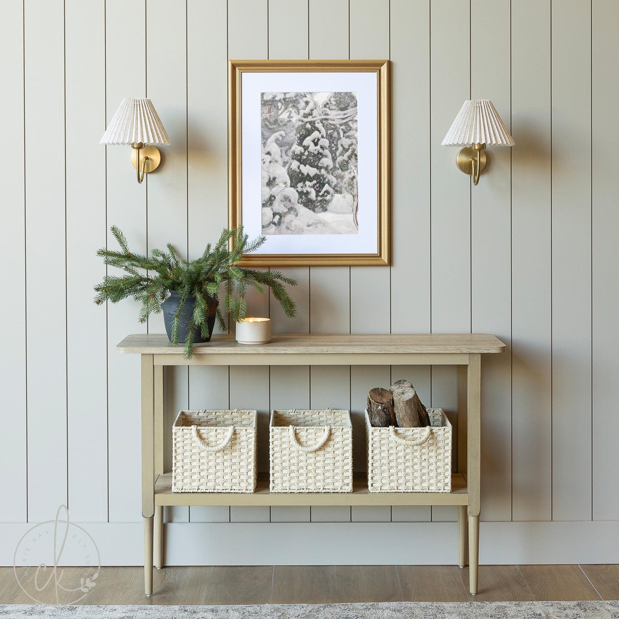 Rustic entryway with framed winter art of snowy pine trees, a wooden console, and woven baskets for cozy décor.