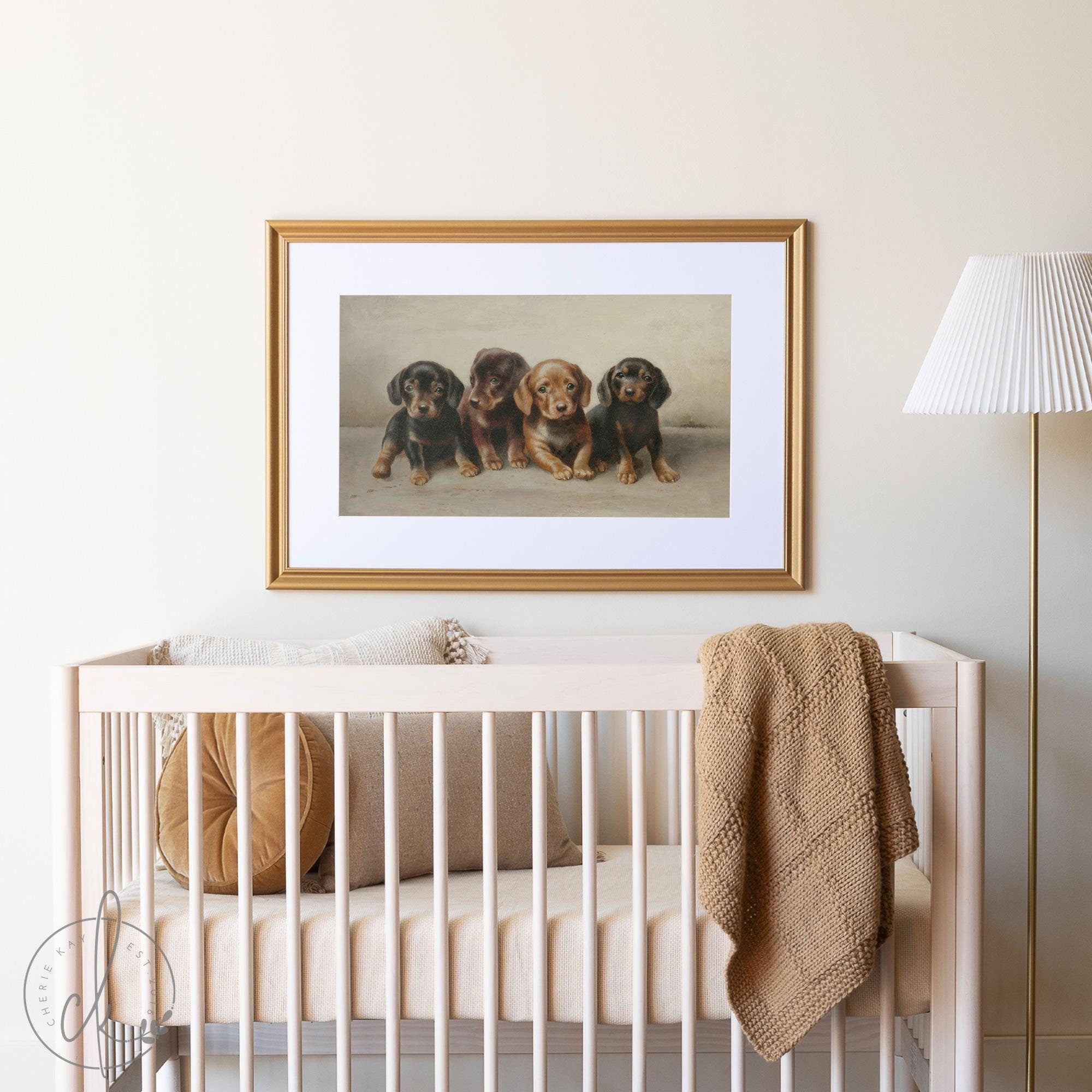 Modern vintage nursery wall art featuring a framed painting of four dachshund puppies in a gold frame, hanging above a neutral-colored baby crib with cozy blankets and pillows. Perfect for baby room or kids&#39; room decor.