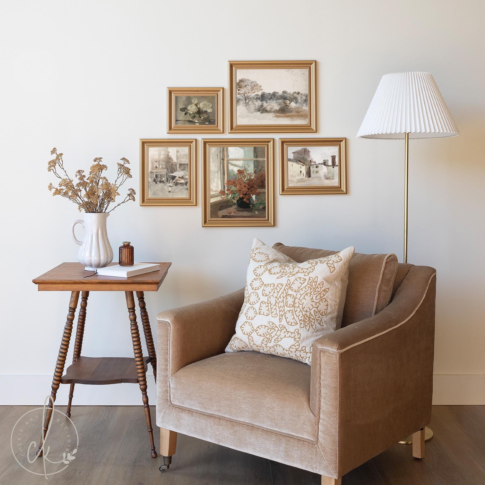 Vintage gallery wall setup featuring gold-framed artwork above a neutral armchair and wooden side table with dried floral decor, creating a warm and inviting reading nook.