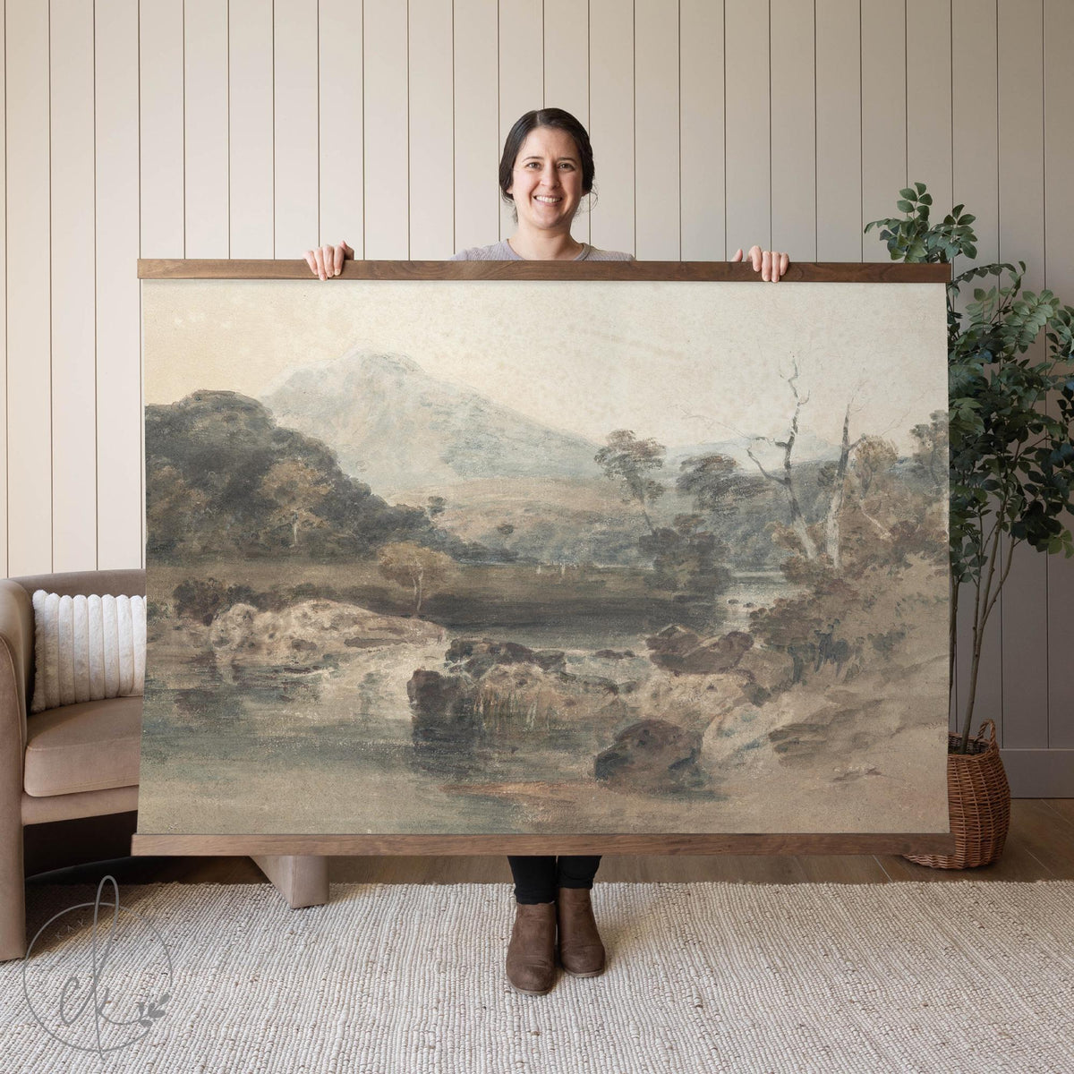 Large framed vintage landscape artwork featuring a serene countryside scene with mountains, trees, and a reflective river in muted earthy tones.