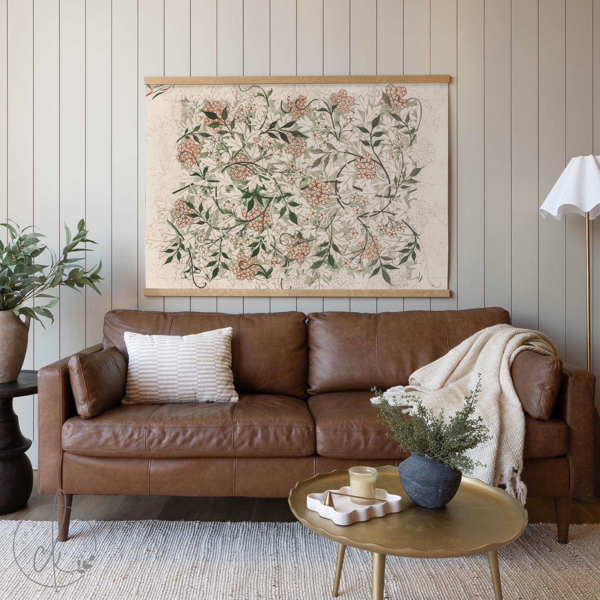 Large vintage botanical wall art featuring an intricate floral design in earthy tones, elegantly displayed above a brown leather sofa in a cozy living room with neutral decor. William Morris