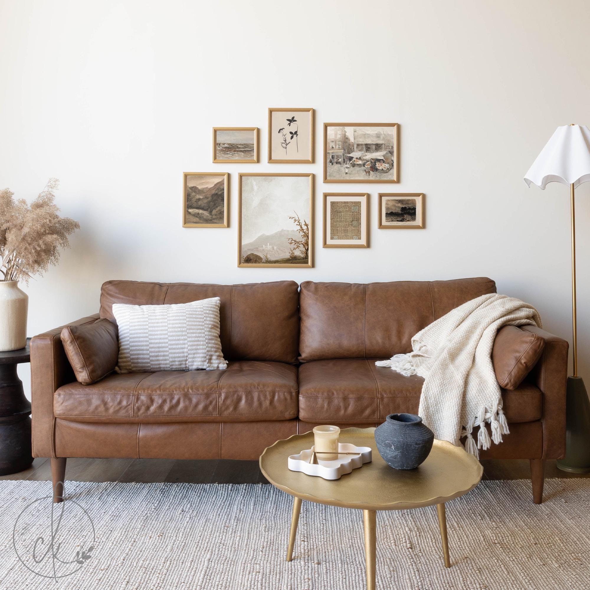 Framed vintage gallery wall art set displayed above a brown leather sofa in a neutral-toned living room, featuring antique-inspired prints in warm, earthy hues.